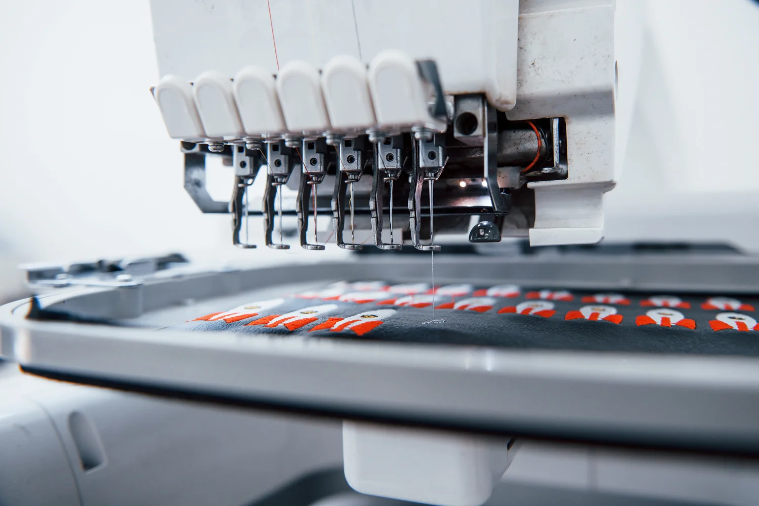 Close up view of white automatic sewing machine making rocket embroidery